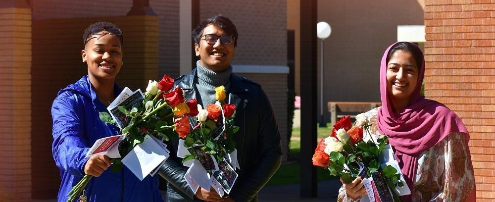 students standing in sunlight with flowers on valentines day